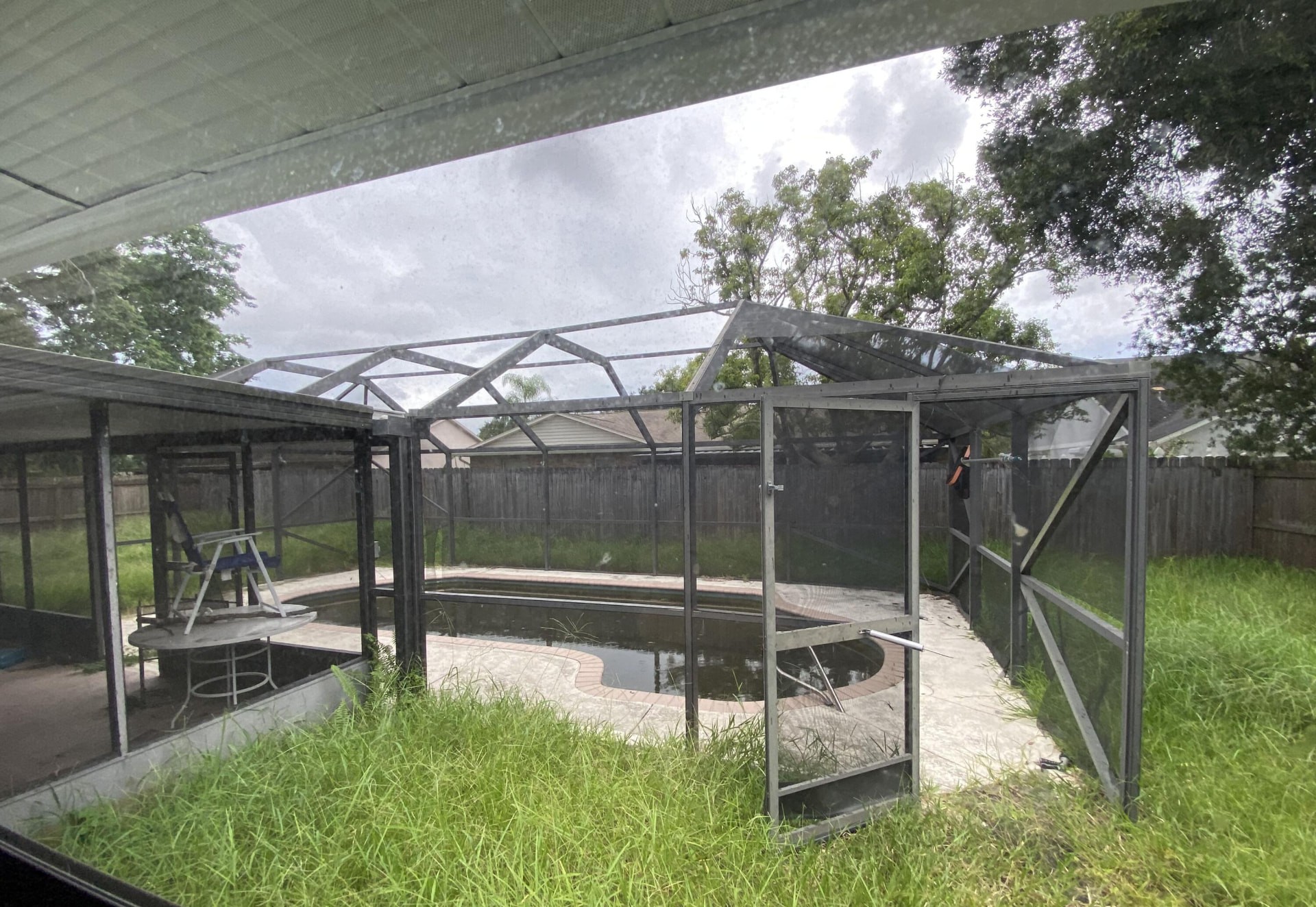 An overgrown pool enclosure at a Florida home purchased by Alexta Homes